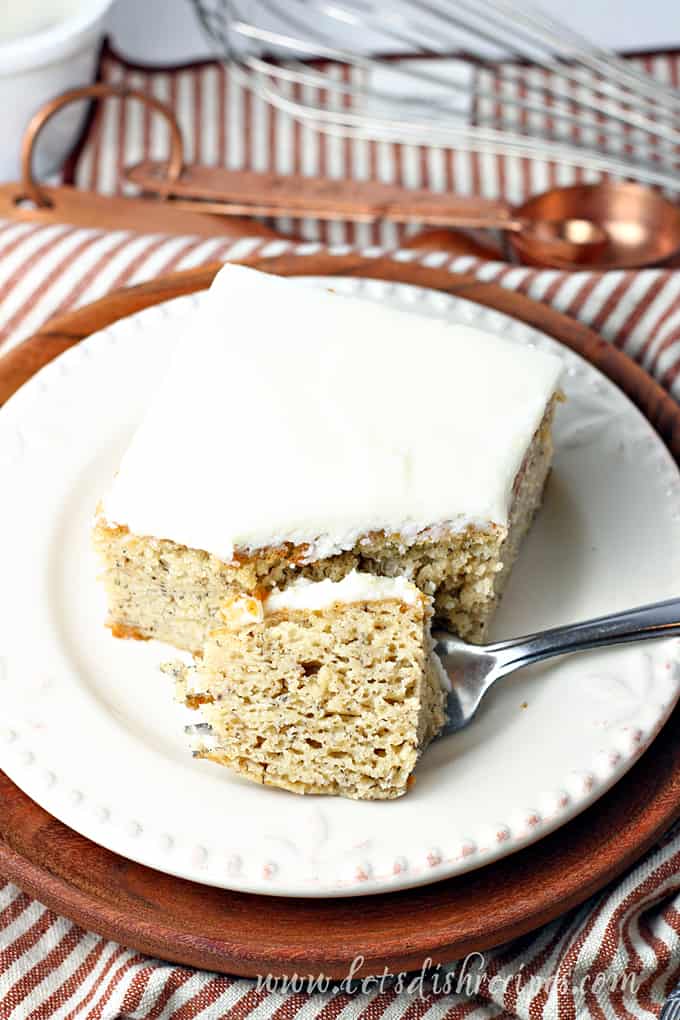 Slice of banana cake with vanilla frosting and fork.