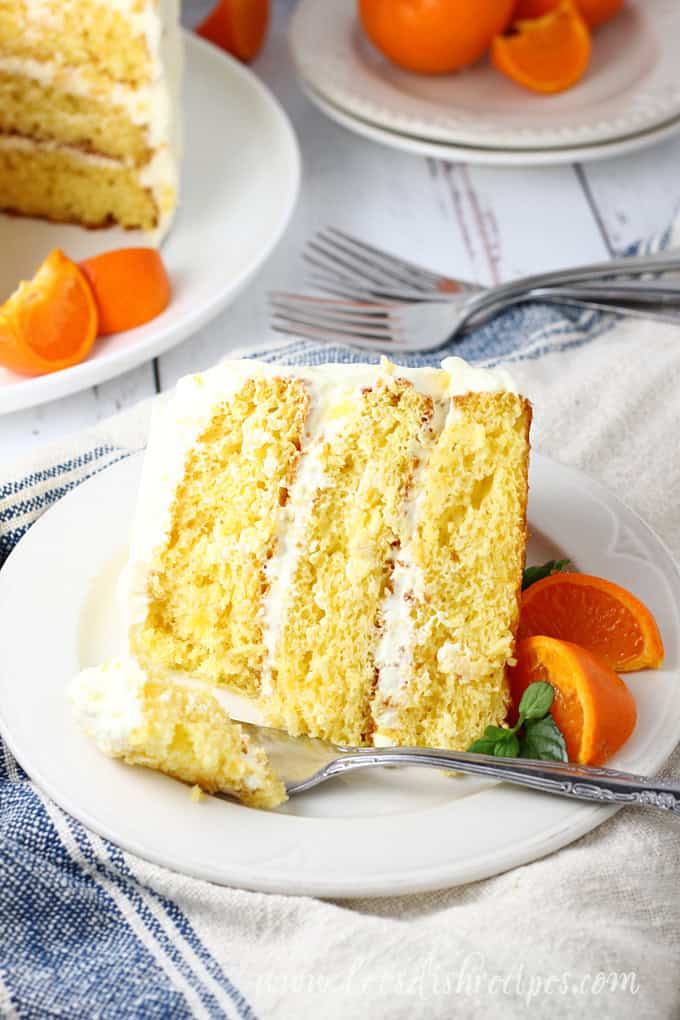 Slice of pineapple orange cake with whipped cream frosting.
