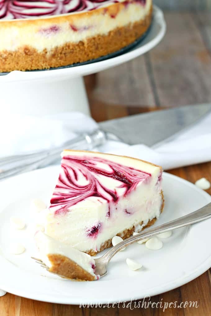 Slice of white chocolate cheesecake with a raspberry swirl on top.
