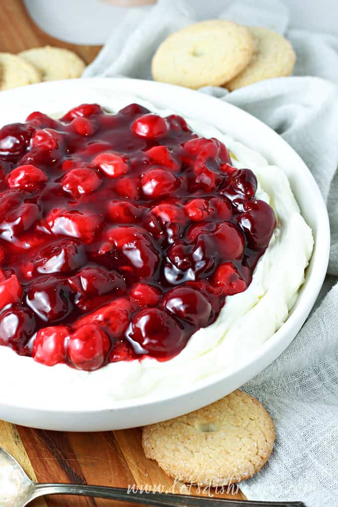 Cheesecake filling topped with cherries and served with cookies.