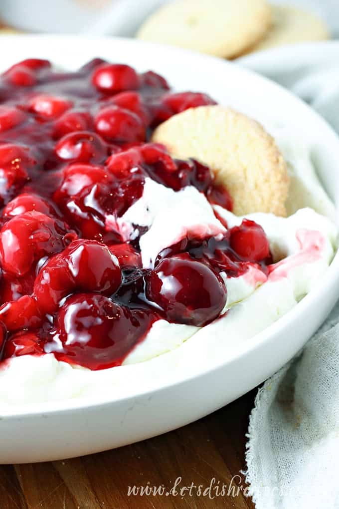 Cheesecake filling topped with cherries and served with cookies.