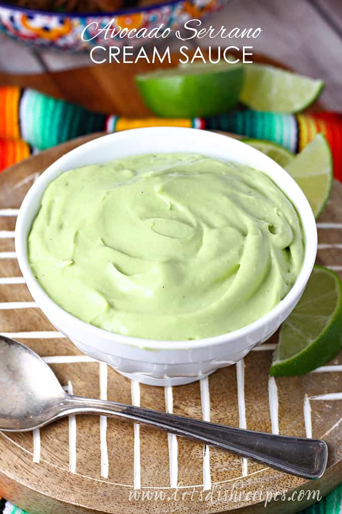 Creamy avocado sauce in bowl with limes.