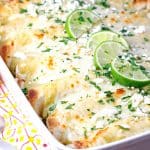 Pan of enchiladas filled with street corn and cheese, topped with lime wedges.