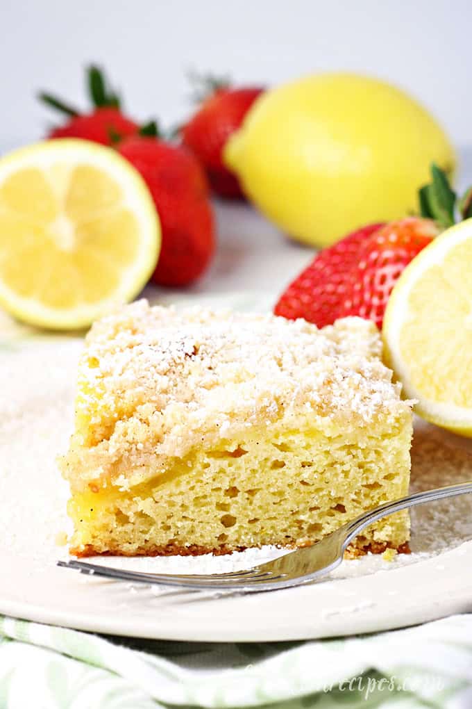 Slice of lemon cake with lemon curd and crumb topping, dusted with powdered sugar.