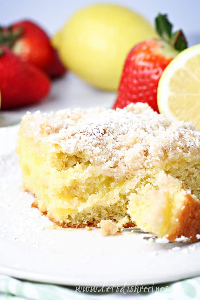 Slice of lemon cake with lemon curd and crumb topping, dusted with powdered sugar.